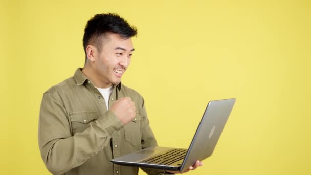 Chinese Man Celebrating Raising Fist While Looking Laptop Studio Yellow — стоковое видео