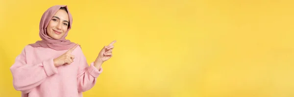 Мусульманская Женщина Показывает Пальцем Пустое Пространство Сторону Студии Желтым Фоном — стоковое фото