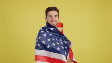 Stüdyoda sarı arka planda Kuzey Amerika bayrağı taşıyan mutlu beyaz adam.