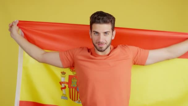 Onnellinen Valkoihoinen Mies Käärimässä Espanjan Lipun Kanssa Studiossa Jolla Keltainen — kuvapankkivideo