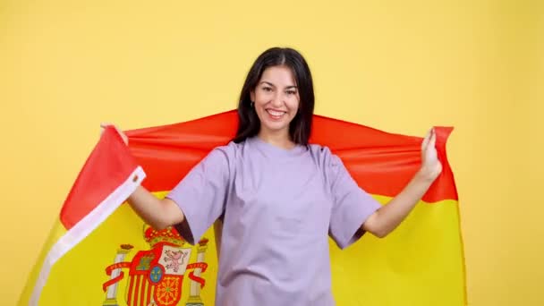 Happy Caucasian Woman Wrapping Spanish National Flag Studio Yellow Background — Vídeo de Stock