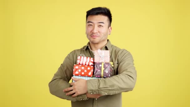 Happy Chinese Man Holing Many Colorful Gifts Studio Yellow Background — Stock Video