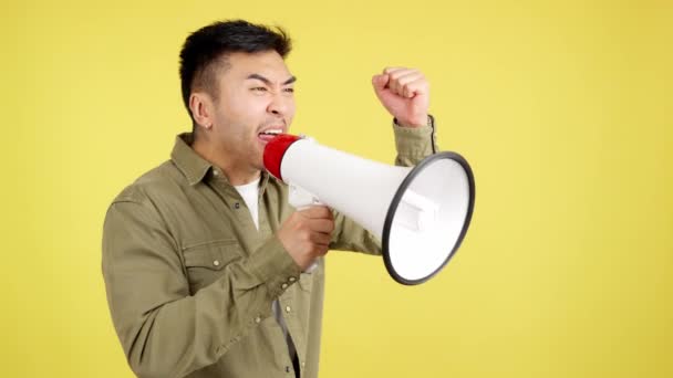 Rozrušený Čínský Muž Křičí Pomocí Reproduktoru Studiu Žlutým Pozadím — Stock video