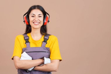 Friendly caucasian woman carpentry worker in work uniform in studio with brown background