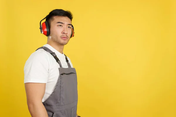 Serious Chinese Worker Headphones Standing Looking Aside Studio Yellow Background — Stock Photo, Image