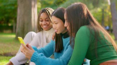 Cep telefonunu kaydıran mutlu mulitetik arkadaşların yavaş çekim videosu ve açık havada gülmeye başlıyorlar.