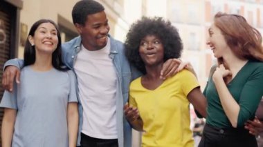 Çok ırklı arkadaşlardan oluşan mutlu bir grubun cadde boyunca birlikte yürüdüğü yavaş çekim videoları.