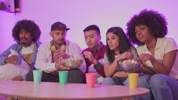 ホーム食べるポップコーンとチップで映画を見ている友人の多民族グループのスローモーションビデオ家で — ストック動画