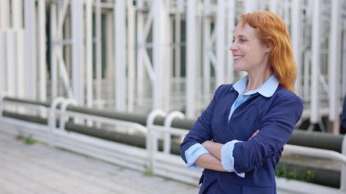 Açık havada gülümseyen mutlu, kızıl saçlı bir iş kadınının yavaş çekim videosu.