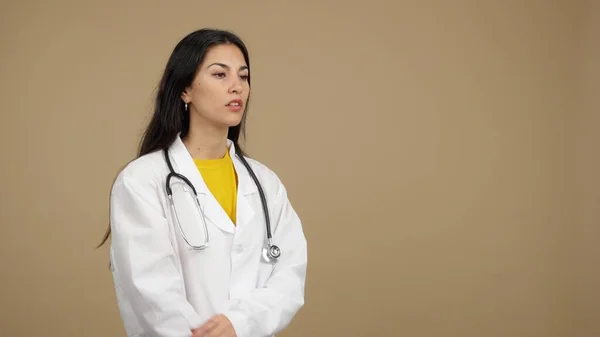 フレンドリーなCaucasian女性医師で制服と聴診器でスタジオで茶色の背景 — ストック写真