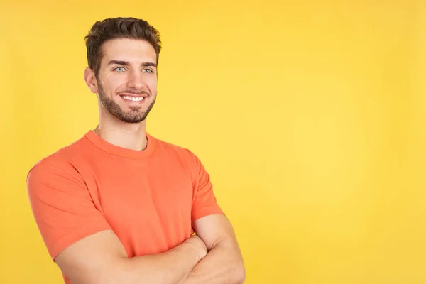 Stock image Happy caucasian man standing with arms crossed in studio with yellow background