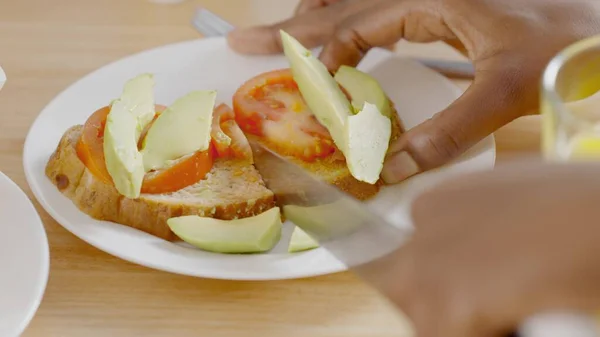 Slow motion close up video of a person cutting a healthy toast of avocado and tomato