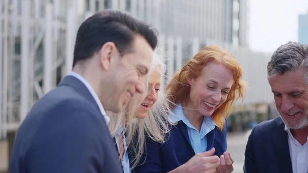 Close up slow motion video of a group of surprised and happy business people looking the screen of a tablet outdoors