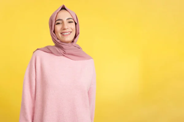 幸せなイスラム教徒の女性笑顔でカメラでスタジオで黄色の背景 — ストック写真