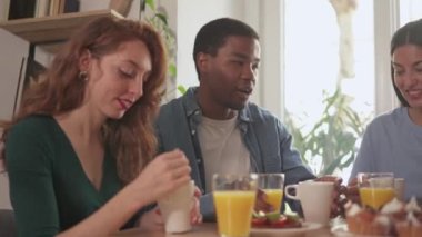 Bir grup mutlu arkadaşın evde birlikte kahvaltı ettiği yavaş çekim videosu.