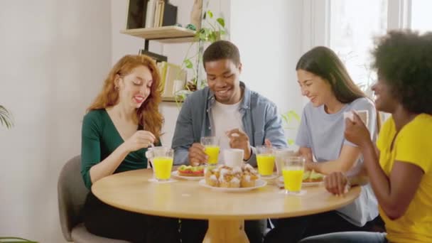 家で朝食を食べながら話す多民族の友人のグループのスローモーションビデオ — ストック動画