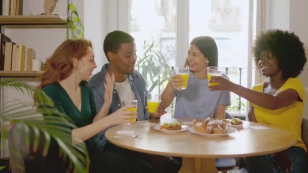 スローモーションビデオのグループの幸せな多民族の友人トーストとともにジュースとともに朝食時に家 — ストック動画