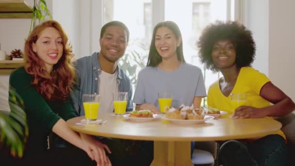 自宅で朝食を食べながらカメラで笑顔の多民族の友人のグループのスローモーションビデオ — ストック動画