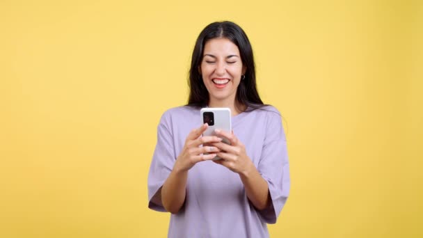 Excited Woman Celebrating While Using Mobile Phone Studio Yellow Background — Vídeos de Stock