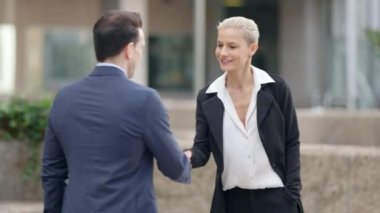 Şehir sokaklarında el sıkışan iş kadını ve işadamının yavaş çekim videosu.