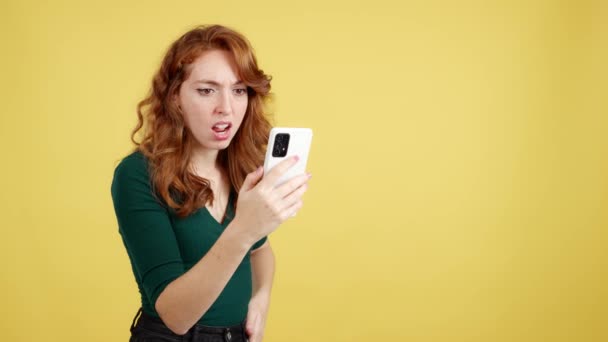 Worried Redheaded Woman Using Mobile Phone Studio Yellow Background — Stock Video