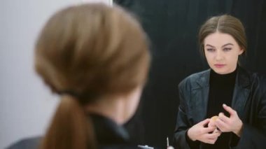 Sahne arkasındaki göz altı dairelerine kapatıcı süren bir kadının yavaş çekim videosu.