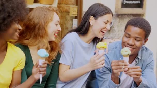路上でアイスクリームを食べながら笑っている多民族の友人のグループのスローモーションビデオ — ストック動画