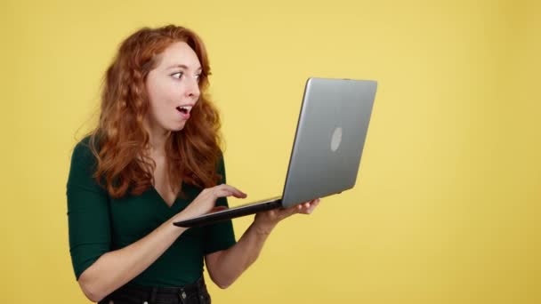 Surprised Redheaded Woman Using Laptop While Smiling Studio Yellow Background — Stock Video