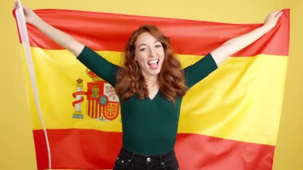 Счастливая Рыжая Женщина Улыбается Поднимает Испанский Национальный Флаг Студии Желтым — стоковое видео