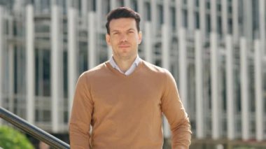 Kameraya gülümseyen mutlu iş adamının kollarını açık havada kavuşturduğu yavaş çekim videosu.