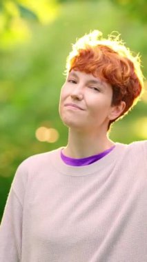 Parkta her şeyin yolunda olduğunu işaret eden ikili olmayan kişi gülümsüyor.