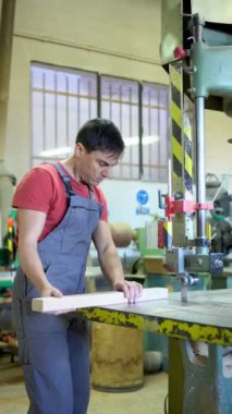 Konsantre olmuş erkek marangoz, hafif marangozlukta çalışırken profesyonel metal testeresiyle uzun tahta kesiyor.