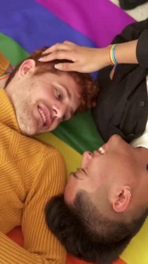 Bir lgbt bayrağının üzerinde yatarken gülümseyen mutlu bir çiftin yavaş çekim videosu.