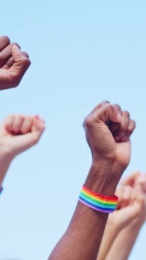 Igbt bilekliği takan ve kollarını sıkı tutan çok ırklı bir grup insanın kırpılmış görüntüsü.