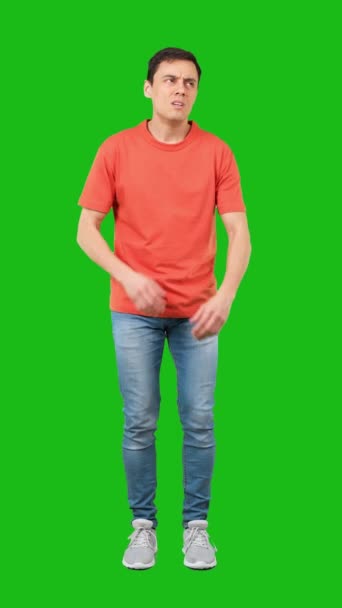 全身疲れた男でオレンジTシャツとジーンズ交差腕と見てカメラで隔離された緑の背景 — ストック動画