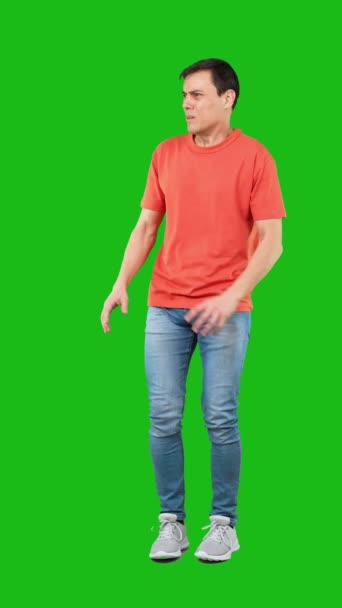 完全長いです恐怖男性でジーンズとオレンジTシャツ作る保護ジェスチャーと離れて見ている間に叫んで恐怖で緑の背景 — ストック動画