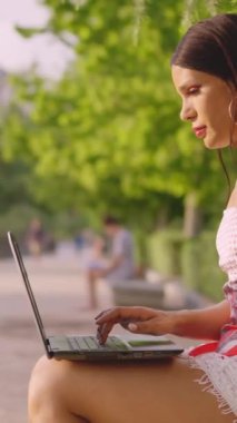 Parkta dizüstü bilgisayar kullanan transseksüel bir kadın.