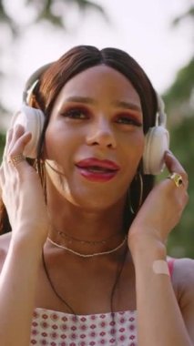 Transgender woman listening music and singing in a park