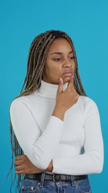 Video with blue background of an african beauty thoughtful woman standing and gesturing concern