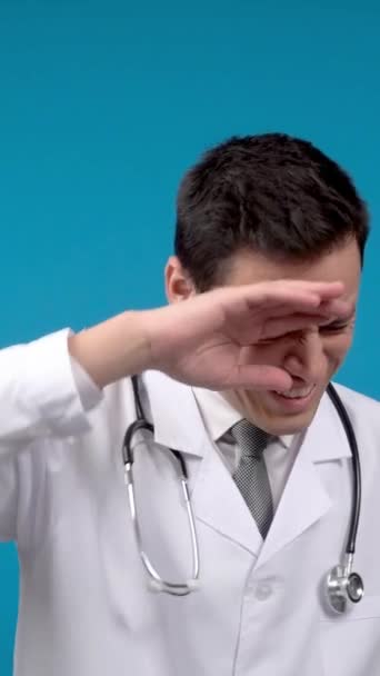 額に触れる聴診器を持つ医師と離れて見ている間に仕事で疲れている青の背景 — ストック動画