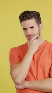 Caucasian man with hand on face and thoughtful expression in studio with yellow background
