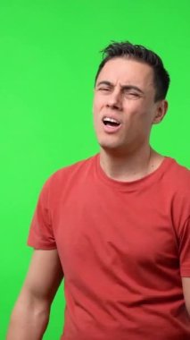 Kırmızı tişörtlü adam çok yorgun, sıkı çalıştıktan sonra zor nefes alıyor. Krom yeşil arkaplan, orta çekim.