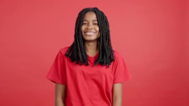 Stüdyoda kırmızı arka planda kameraya gülümseyen mutlu Afrikalı kadın.
