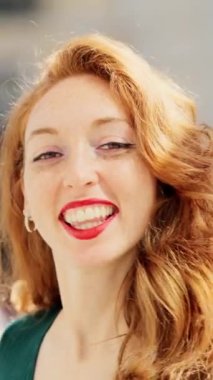 Kızıl saçlı bir kadının kameraya bakıp gülümsemesinin yavaş çekim videosu.