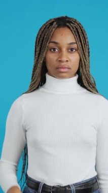 Video with blue background of an african woman with the palm of her hand gesturing stop