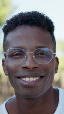 Parkta kameraya gülümseyen Afrikalı genç bir adam.