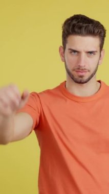 Caucasian man gesturing prohibition with hand in studio with yellow background