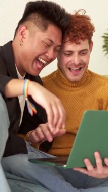 Evdeki kanepede dizüstü bilgisayar kullanarak gülen mutlu bir çiftin yavaş çekim videosu.