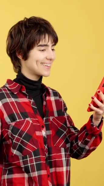 Андрогінна Людина Посміхається Відправляючи Повідомлення Мобільним Телефоном Студії Жовтим Фоном — стокове відео