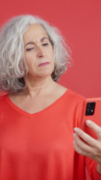 Studio Video Red Background Worried Mature Woman Using Mobile Phone — Stockvideo